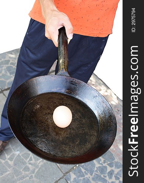 The person holds a frying pan with an egg