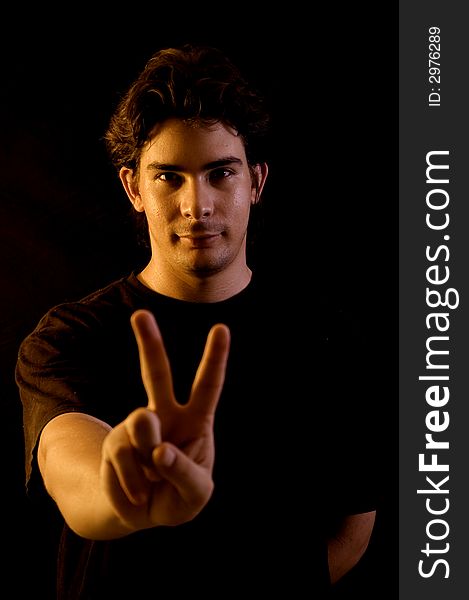 Young male portrait doing peace sign with a hand - black background. Young male portrait doing peace sign with a hand - black background