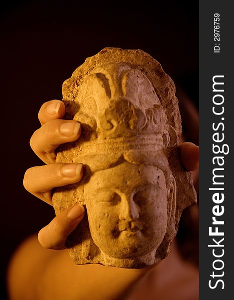 Close up of hand holding a stone buddha statue over black background. Close up of hand holding a stone buddha statue over black background