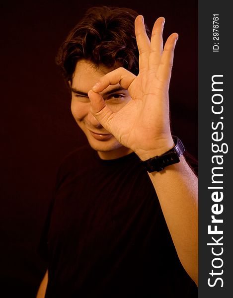 Young male portrait doing OK sign with a hand - black background. Young male portrait doing OK sign with a hand - black background