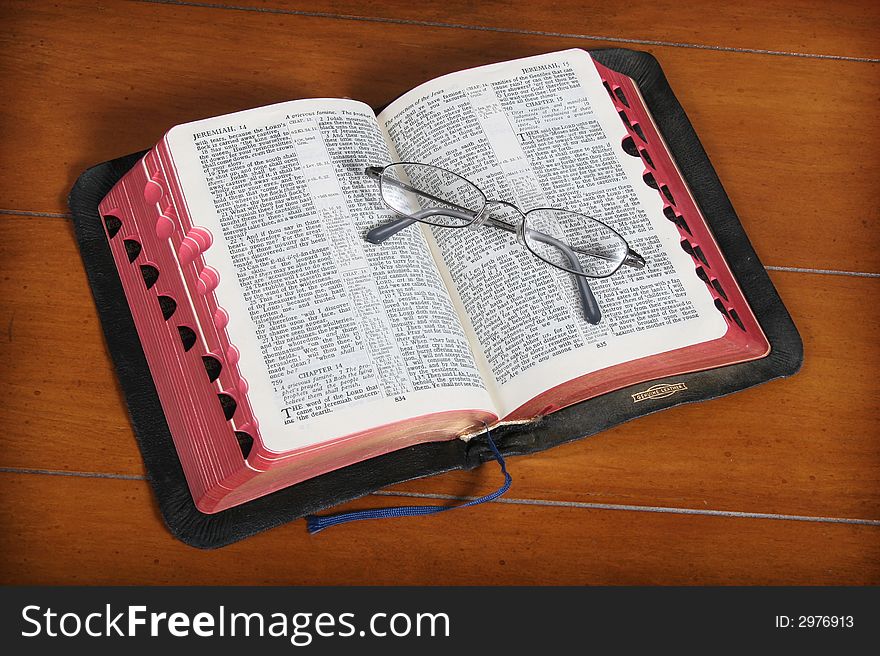 Open Bible with eyeglasses on a wooden table. Open Bible with eyeglasses on a wooden table.