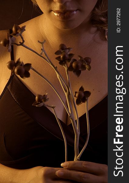 Detail of womanÂ´s face and hands holding flowers on dark background. Detail of womanÂ´s face and hands holding flowers on dark background