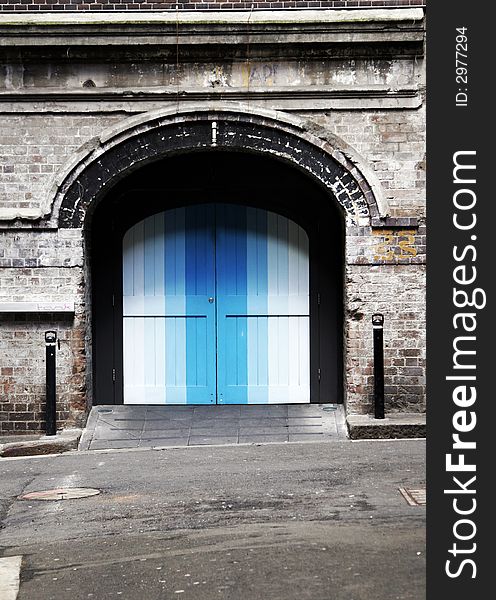 Colourful Blue Door In An Old Brick Wall, Backstreet Entrance, Background. Colourful Blue Door In An Old Brick Wall, Backstreet Entrance, Background