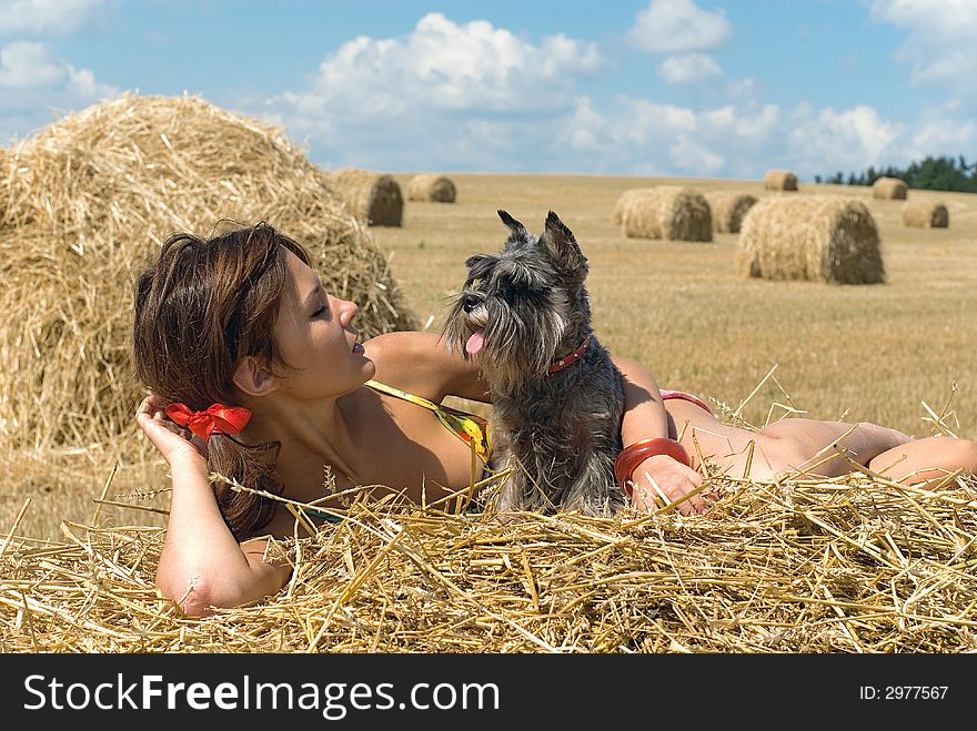 The girl lays on a haystack with dog. The girl lays on a haystack with dog