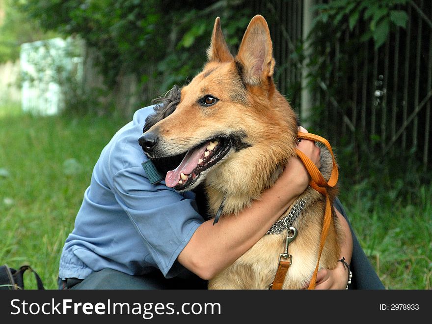 A policeman embraces his dog. A policeman embraces his dog