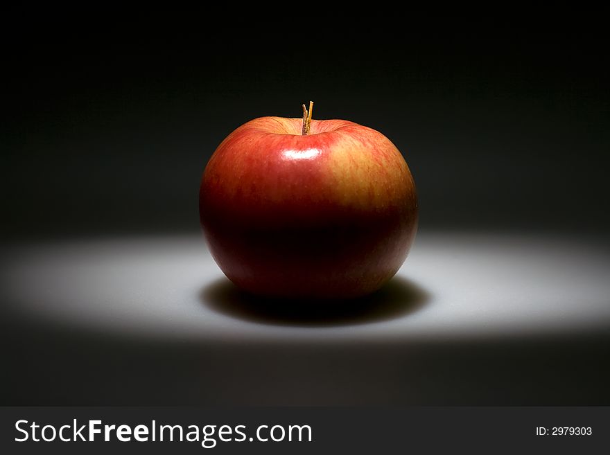 Black background with highlighted red apple in the center. Black background with highlighted red apple in the center.