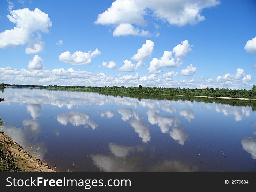 Calm, river waters reflect the sky with clouds. Calm, river waters reflect the sky with clouds