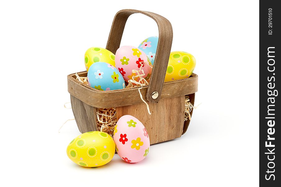 Painted, multi colored easter eggs in a basket, isolated on white background
