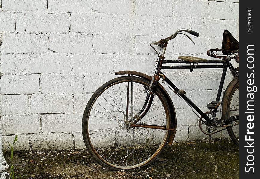 An old classic bike in front of white concrete wall. An old classic bike in front of white concrete wall