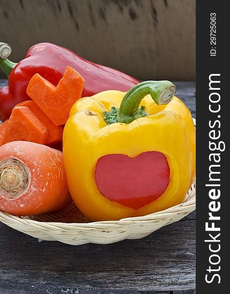 Sweet pepper and carrot in bamboo basket over wood background. Sweet pepper and carrot in bamboo basket over wood background