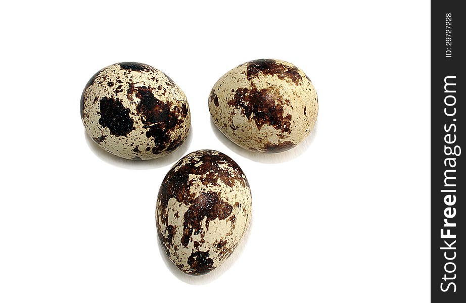 Three quail eggs on white background with light shadow