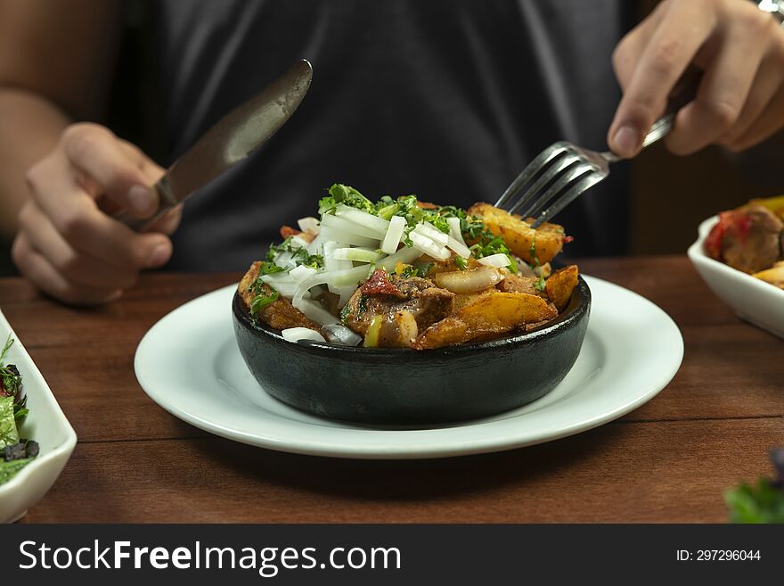 Man eating Beef stew with potatoes, carrots and herbs on black background with copy