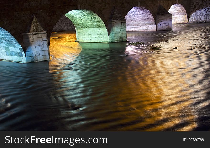 Old Stone Bridge Arch Over A River at night
