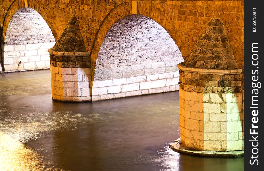 Old Stone Bridge Arch Over A River at night