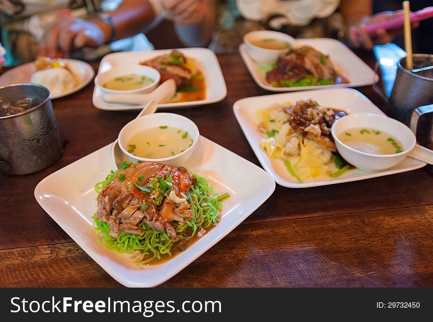 Green noodles with roasted duck on wood desk