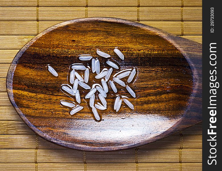 Grain of rice on wet wooden spoon