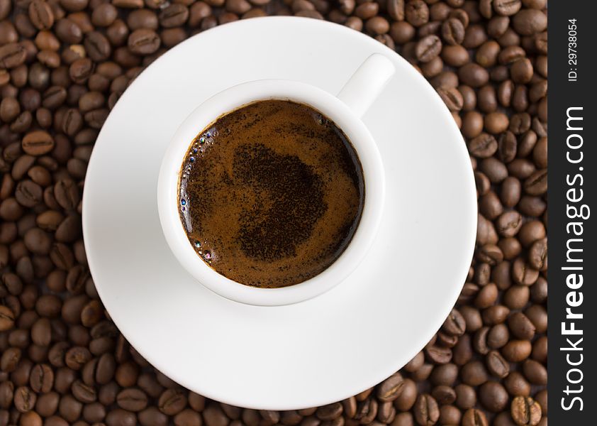 White cup of coffee on coffee beans background