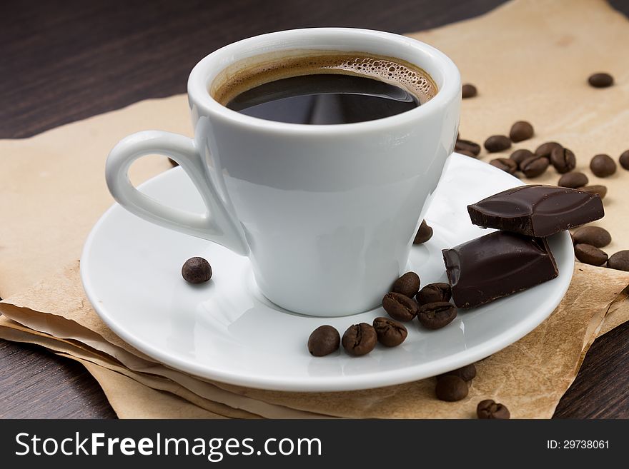 Cup of coffee and beans with chocolate on paper background