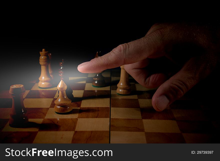 The photo shows the board game of chess in which the chess pieces are. Of the board, we see a male hand which finger points to a chess pawn. The photo shows the board game of chess in which the chess pieces are. Of the board, we see a male hand which finger points to a chess pawn.