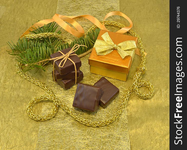 Set of chocolate gift with conifer branch on the gold background. Set of chocolate gift with conifer branch on the gold background