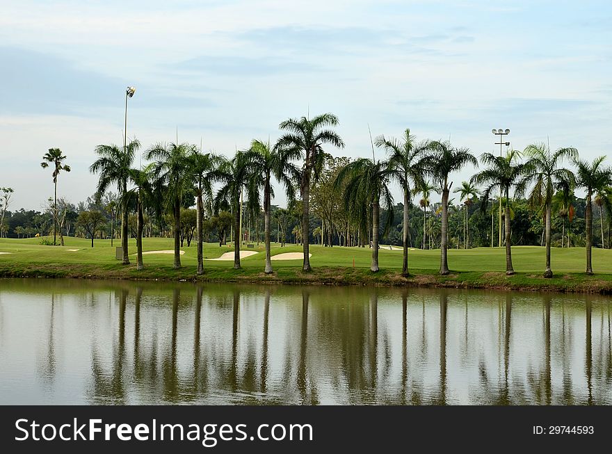 A scenic view of a golf course looking over a lake, showing sand traps, palm trees, clear blue sky and some golfers. A scenic view of a golf course looking over a lake, showing sand traps, palm trees, clear blue sky and some golfers.