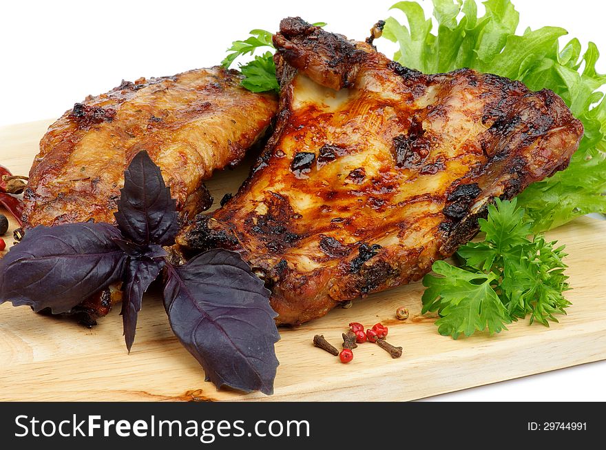 Delicious Barbecue Pork Ribs with Greens and Basil closeup on Cutting Board