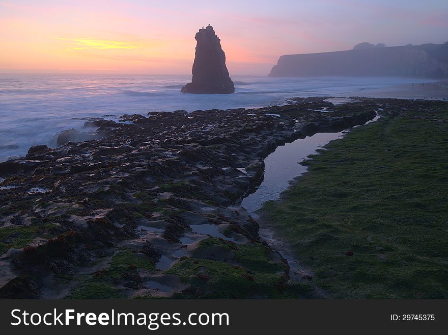 Davenport Beach Sunset, with rock formation in the forground and smooth tides;