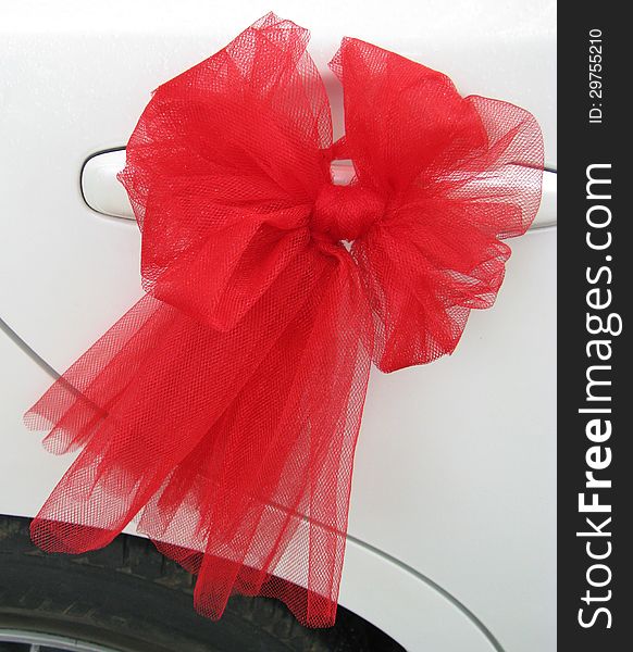 A red bow of lace ribbon for a wedding on a car. A red bow of lace ribbon for a wedding on a car