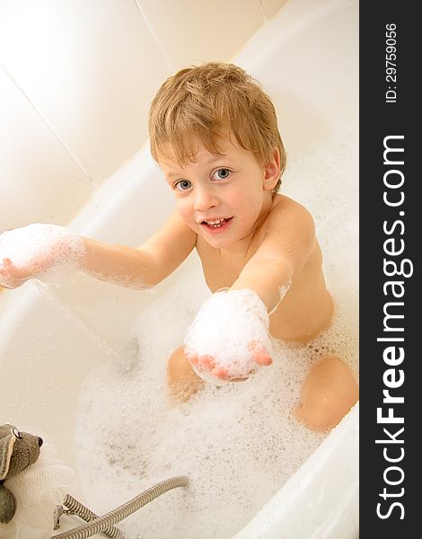 Cute three year old boy taking a bath with foam