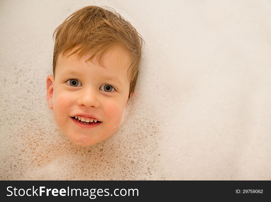 A baby in a bathtub with soap foam. This image has attached release.