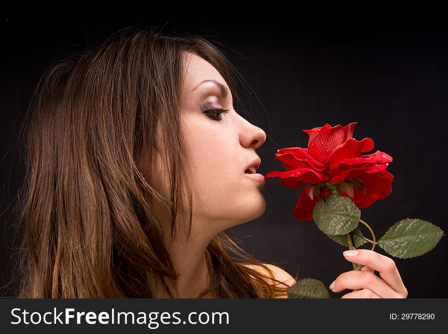 Portrait of a girl who is holding a rose. Behind the dark background. Portrait of a girl who is holding a rose. Behind the dark background.