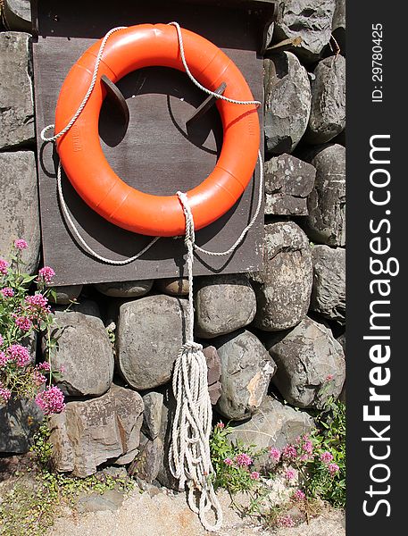 An Orange Rescue Ring Hanging on a Harbour Wall. An Orange Rescue Ring Hanging on a Harbour Wall.