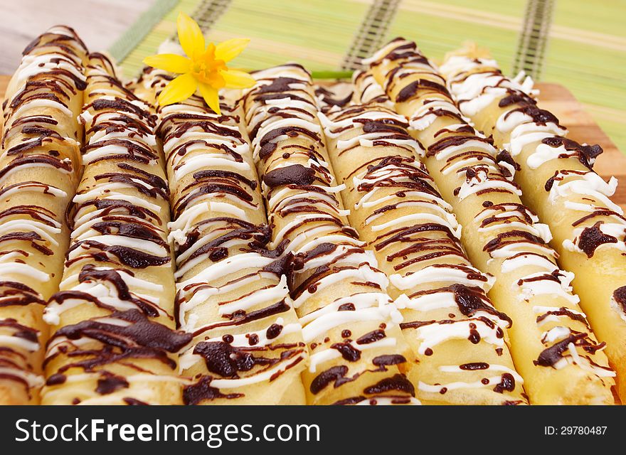 Pancakes topped with chocolate on the wooden plate