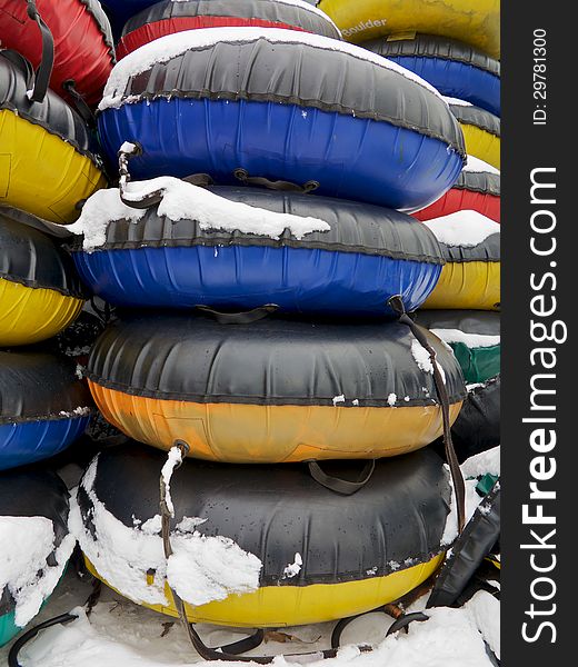 Stacks of red, yellow, blue, and green snow tubes are shown in the snow, vertical shot. Stacks of red, yellow, blue, and green snow tubes are shown in the snow, vertical shot.