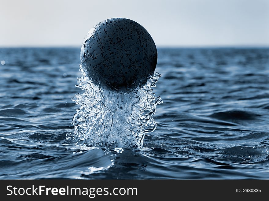 Emersion of  black ball on a background of an evening  seascape(cyan toned). Emersion of  black ball on a background of an evening  seascape(cyan toned)