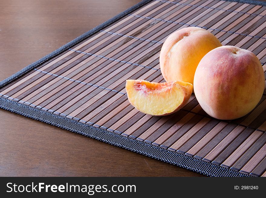 Two juicy peaches on a bamboo napkin. Two juicy peaches on a bamboo napkin