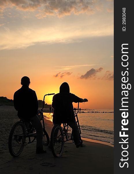 Bikers admiring sunrise during cloudy day