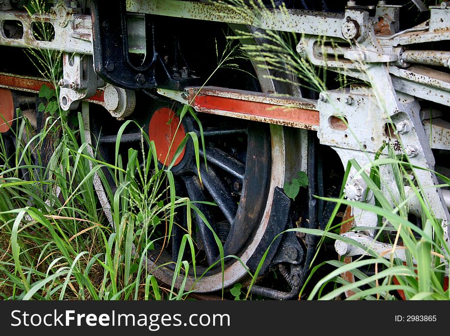 Close up of old steam engine wheel overgrown with grass. Close up of old steam engine wheel overgrown with grass.