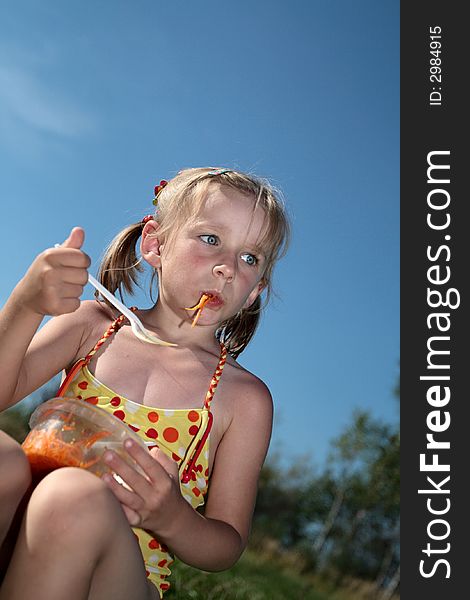 The girl eats salad at summer outdoor