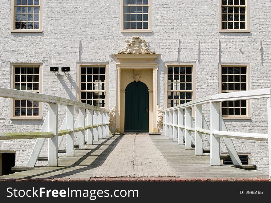 Entrance of a white castle (building) with bridge, door and seven windows. Shot at a sunny day in the summer.