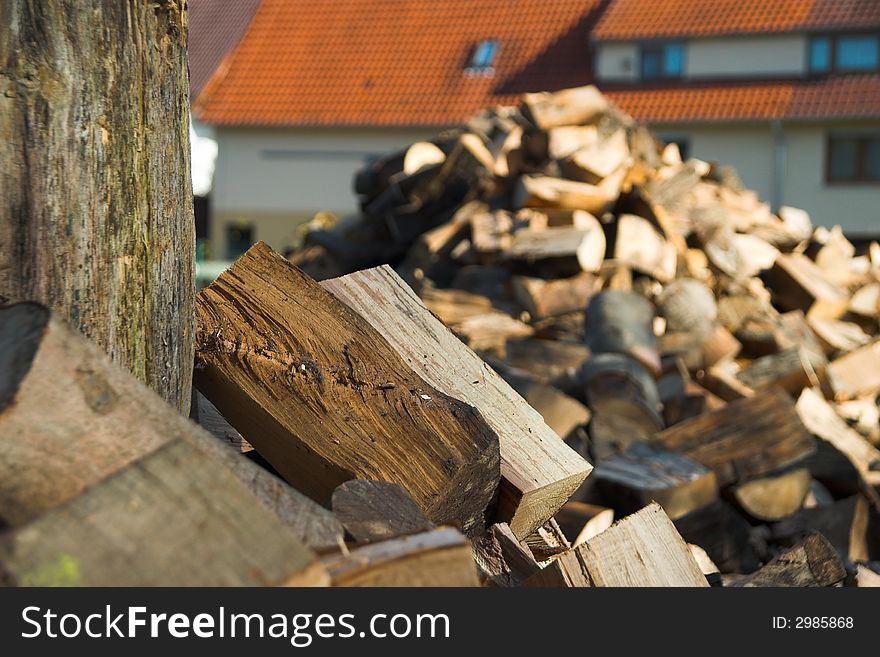 Pile of split fire wood with a house in the background. Pile of split fire wood with a house in the background.