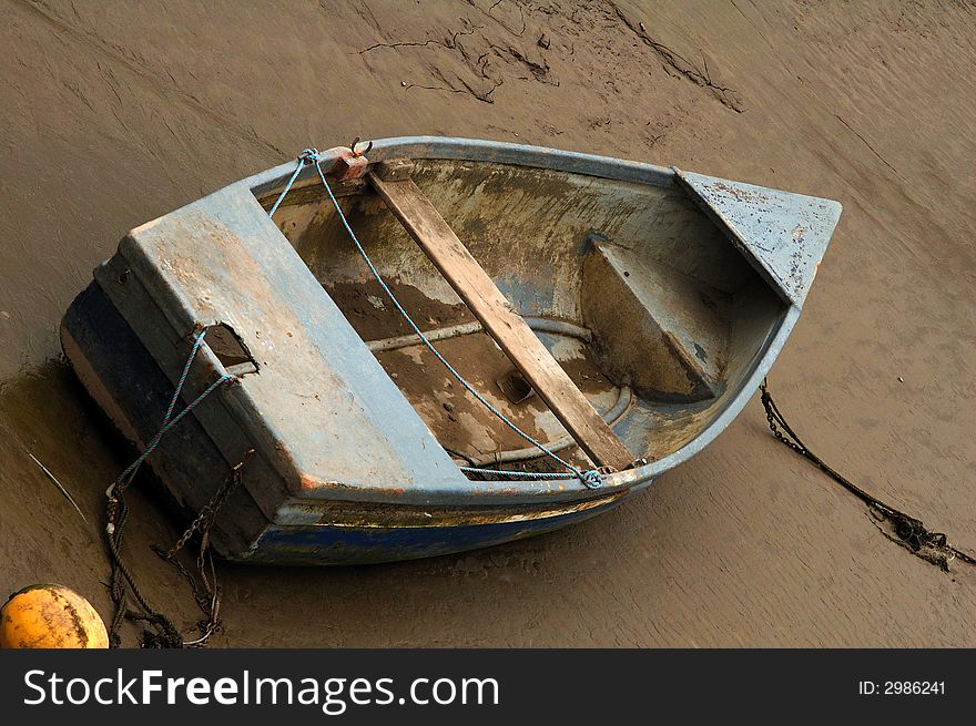 Old and weathered rowing boat tied up and beached on the sand. Old and weathered rowing boat tied up and beached on the sand
