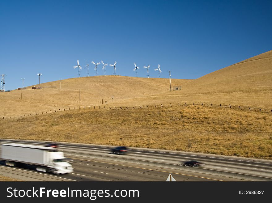 Rushing cars on a national freeway between yellow grass hills with windturbine in California. Rushing cars on a national freeway between yellow grass hills with windturbine in California