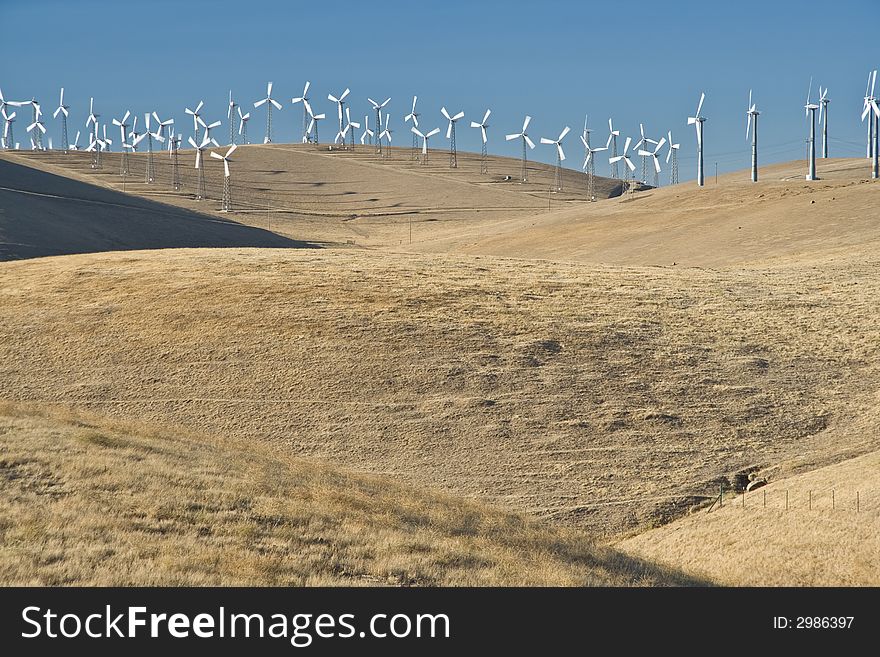 Windfarm turbines on yellow grassed hills with blue cloudless skys. Windfarm turbines on yellow grassed hills with blue cloudless skys.