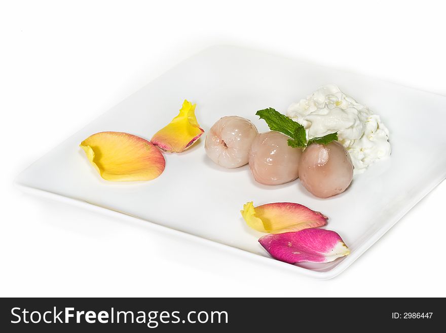 Lychees and whipped cream on white plate, decorated with flowers. Lychees and whipped cream on white plate, decorated with flowers