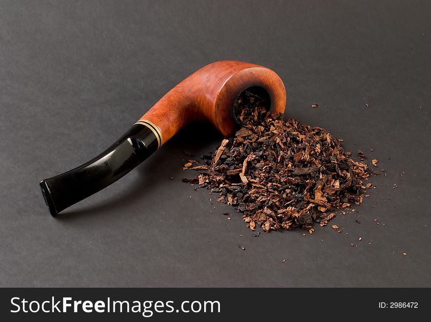 Briar smoking pipe with tobacco on dark background