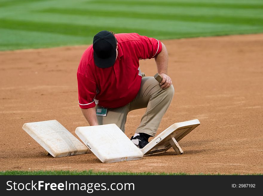 A man prepares third base before a baseball game. A man prepares third base before a baseball game.