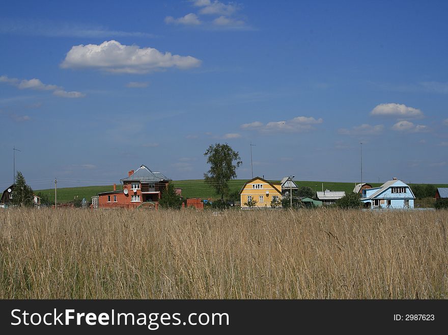 The village houses and the green field landscape and blue sky with clouds as a background. The village houses and the green field landscape and blue sky with clouds as a background.