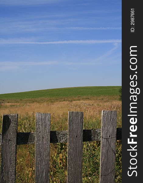 The village fence and the green field and blue sky as a background.