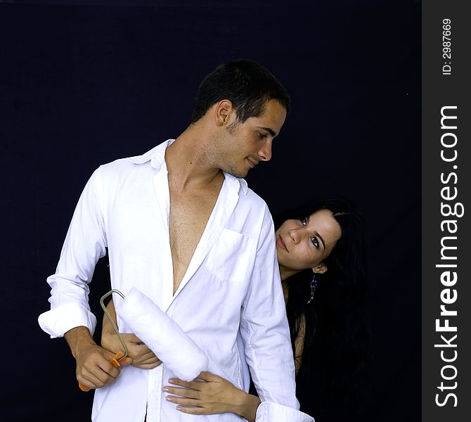 Young hispanic couple holding a painter roller - isolated over black. Young hispanic couple holding a painter roller - isolated over black